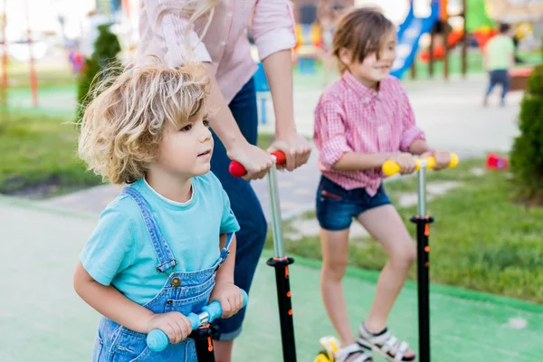 Beskuren Bild Mor Ridning Sparkcyklar Med Son Och Dotter Lekplats — Stockfoto