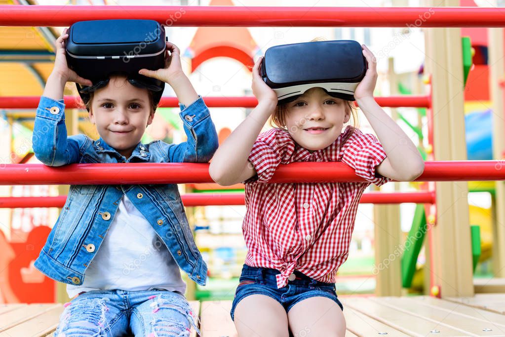 adorable little children taking off virtual reality headsets at playground 