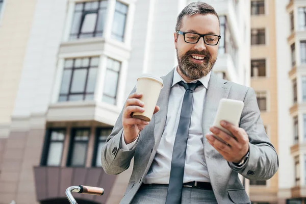 用智能手机和手持纸杯咖啡的大胡子商人 — 免费的图库照片
