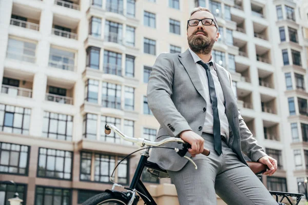 市内で自転車にもたれのスーツでハンサムな実業家  — 無料ストックフォト
