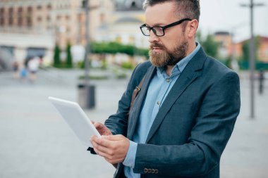 yakışıklı sakal işadamı bardaklarda şehirde dijital tablet kullanma