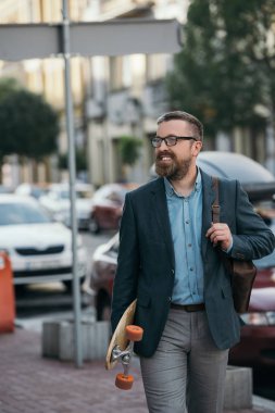 yakışıklı adam deri sırt çantası ve şehirde yürüyüş kaykay sakallı