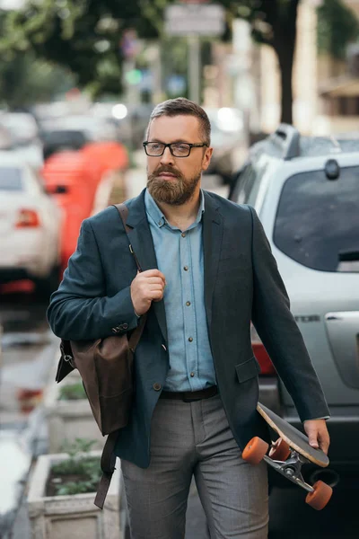 Elegante Hombre Barbudo Guapo Con Mochila Cuero Monopatín Caminando Ciudad — Foto de stock gratuita