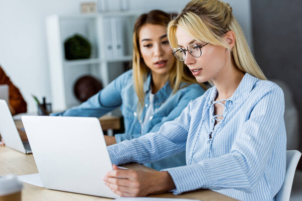 multicultural colleagues working on startup project in office and looking at laptop