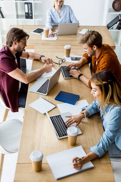 high angle view of young multicultural colleagues working on startup project in office with gadgets