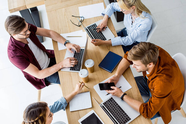 high angle view of colleagues working on startup project in office and using gadgets