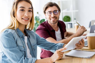 Office başlangıç proje üzerinde ve kameraya bakarak çok kültürlü meslektaşları gülümseyen