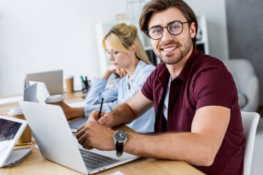 Office başlangıç proje üzerinde ve gülümseyen adam kameraya bakan arkadaşları