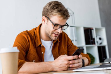 Office başlangıç proje üzerinde ve smartphone kullanarak yakışıklı işadamı