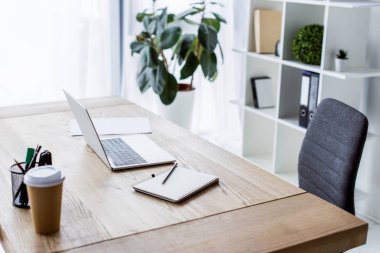 laptop and coffee in paper cup on table in business workspace clipart