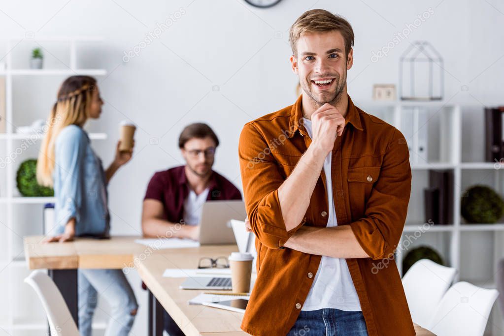 smiling handsome man leaning on table in start up office