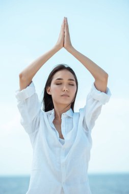 Genç Asyalı kadın kapalı gözlerle asana vrikshasana (ağaç poz) deniz yoluyla ayakta
