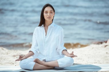 ardha padmasana (yarım lotus poz) yoga mat deniz tarafından meditasyon odaklı kadın 