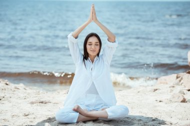 Asyalı Genç kadın meditasyon Lotus pozisyonu ve namaste mudra yapıyor odaklı jest deniz tarafından başının üstünde 