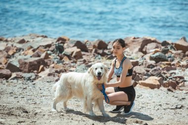 Genç Asyalı kadın kucaklayan köpek deniz önünde sahilde