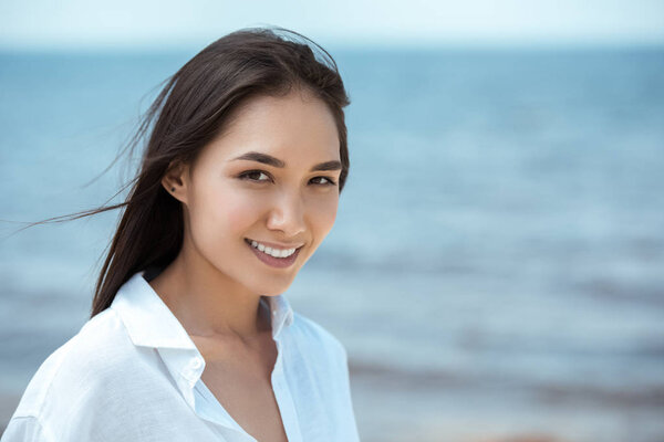 close up portrait of attractive smiling asian woman by sea 