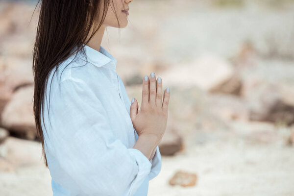 partial view of young woman doing namaste mudra gesture 