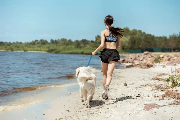 Visão Traseira Corredor Fêmea Correndo Com Cão Praia Perto Mar — Fotografia de Stock