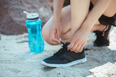 kadın atlet spor şişe su ile yakınındaki ayakkabı bağcığı bağlama kırpılmış görüntü 