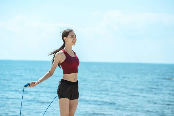 Lächelnde Asiatische Sportlerin Beim Turnen Mit Springseil Vor Dem Meer — Stockfoto
