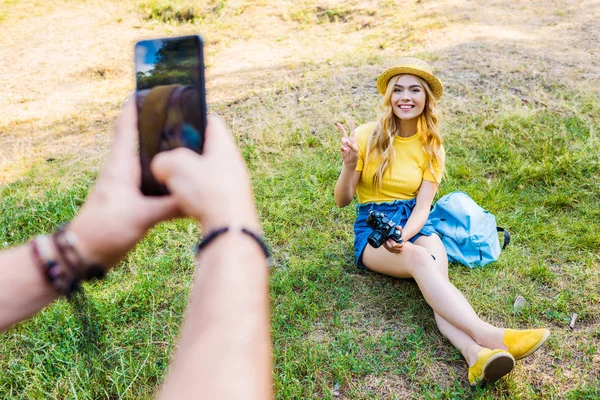 Mann Fotografiert Lächelnde Freundin Auf Grünem Rasen Park — kostenloses Stockfoto