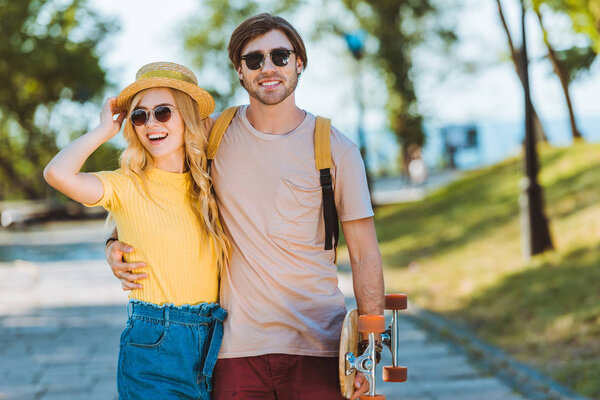 portrait of smiling couple with longboard on summer day