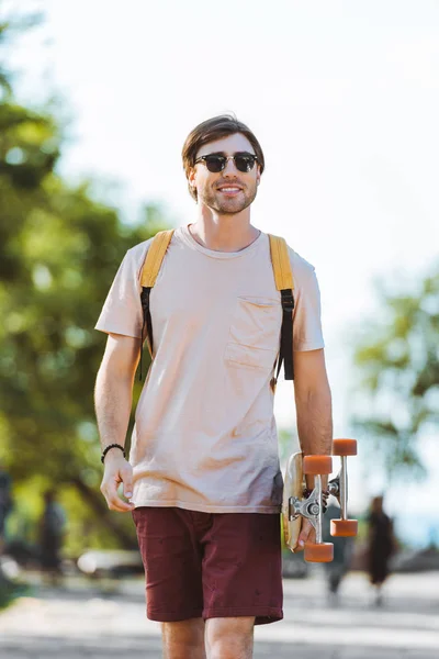 Portret Van Jonge Mens Zonnebril Met Rugzak Longboard Lopen Straat — Stockfoto