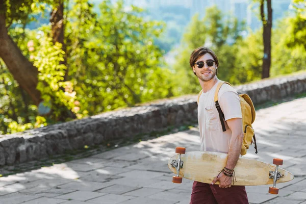 Side View Smiling Man Sunglasses Backpack Longboard Street — Free Stock Photo