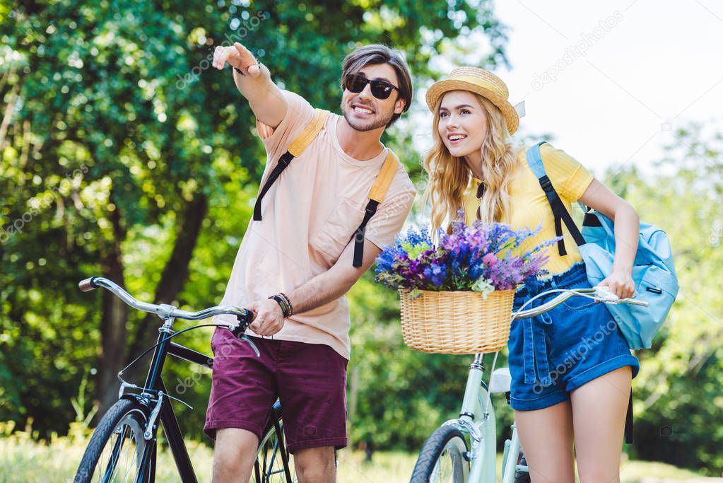 portrait of young couple with backpacks and bicycles in park