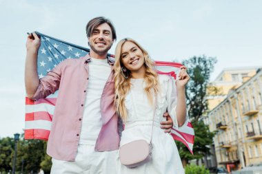 Amerikan bayrağı elinde, Amerika bağımsızlık günü kavramı tutan mutlu genç çift