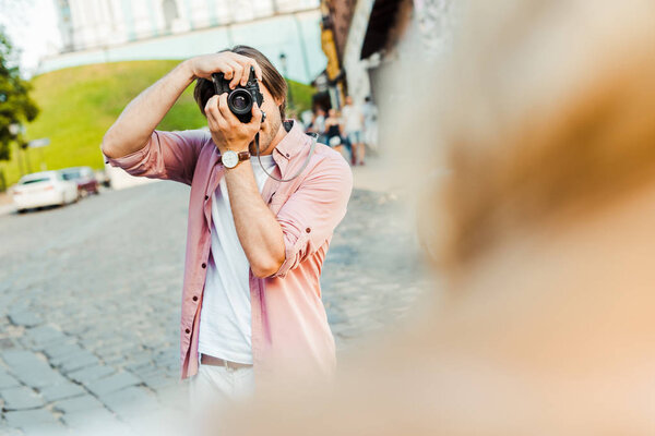 partial view of man taking picture of girlfriend on photo camera on street