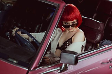 güneş gözlüğü, sutyen ve klasik otomobil sürüş ve uzağa bakarak trençkot güzel kadının yüksek açılı görünüş