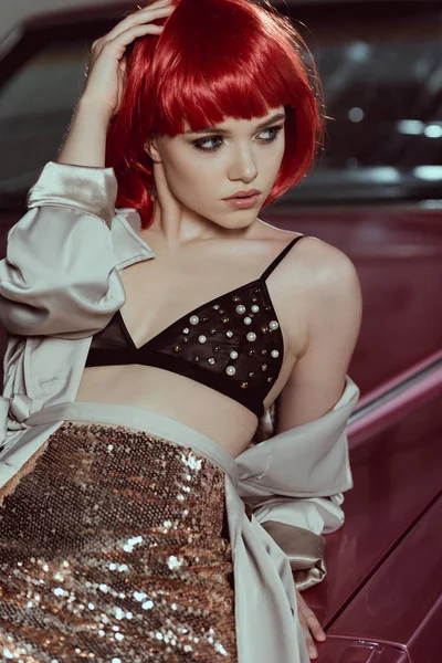 赤いかつらと車で傾いているとよそ見ブラジャーで美しい若い女性 — ストック写真