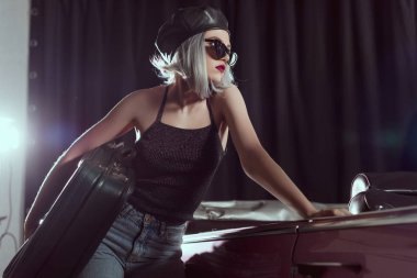 güzel genç kadın güneş gözlüğü ve vintage çanta tutarak ve uzağa süre eğilerek klasik otomobil, seyir bere 