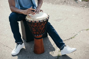 Cropped view of African american man with djembe performing on street clipart