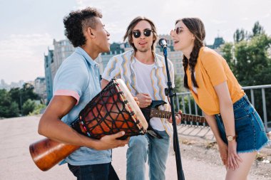 Takım kentsel ortamda mikrofon tarafından şarkı müzik aletleri ile genç arkadaşlar
