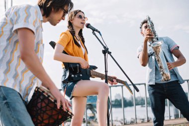 Gitar, djembe ve güneşli şehir sokak müzik saksafon çok ırklı gençlerle