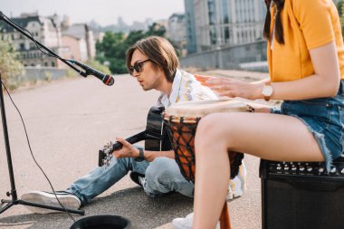 Genç mutlu kadın davulcu ve erkek gitarist City sokak