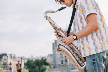 Genç hipster adamla sokakta gerçekleştirme saksafon