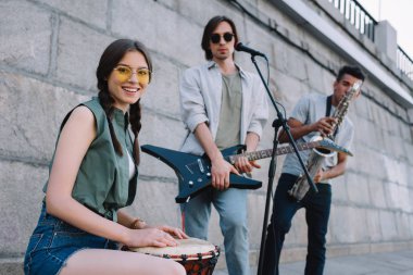 Genç hipster buskers şehir sokak oynarken müzik aletleri ile