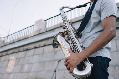 Afrika kökenli Amerikalı adam güneşli şehir sokak üzerinde performans saksafon oynamaya görünümünü kırpılmış