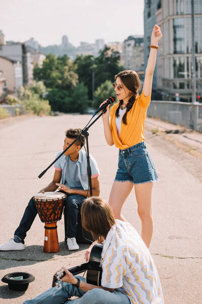 Young happy men and woman buskers playing music at city street