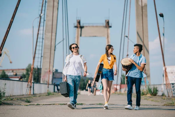 日当たりの良い街で楽器を運ぶ若い男性と女性大道芸人 — ストック写真