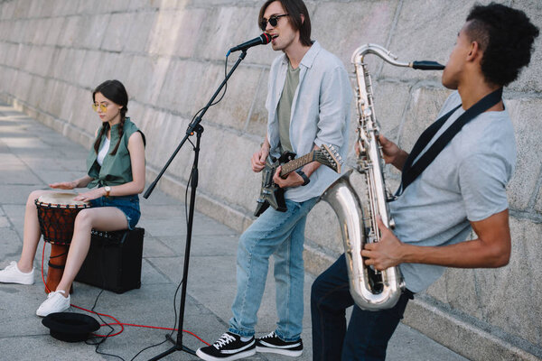 Команда молодых друзей музыканты играют и поют в городской среде
