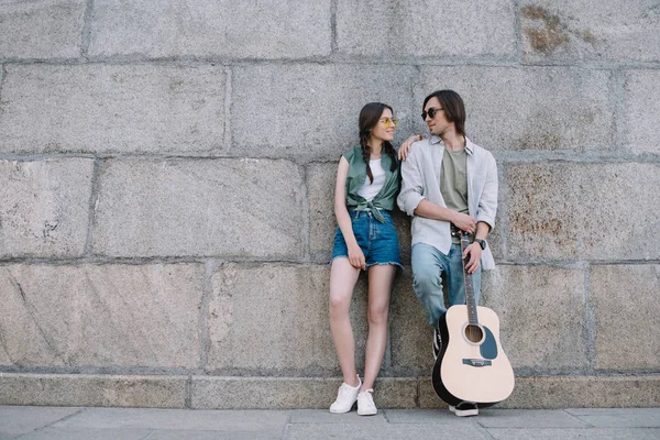 Çekici kız ve adam ile birbirine güneşli şehir sokak bakarak gitar gitar ile