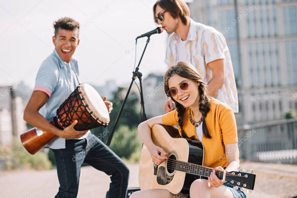 Multiracial young people performing om different musical instruments on street