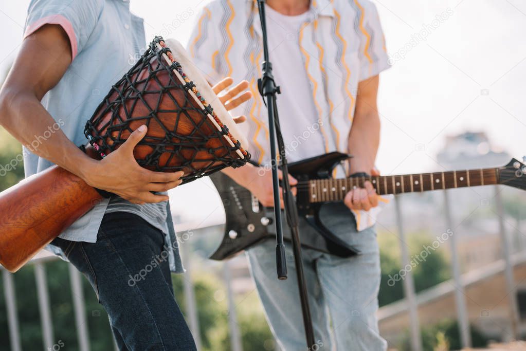 Cropped view of multiracial men performing on sunny city street