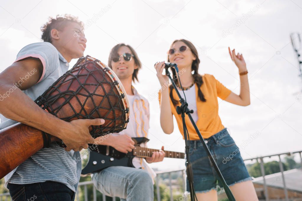 Young and happy street musicians playing music and singing in city