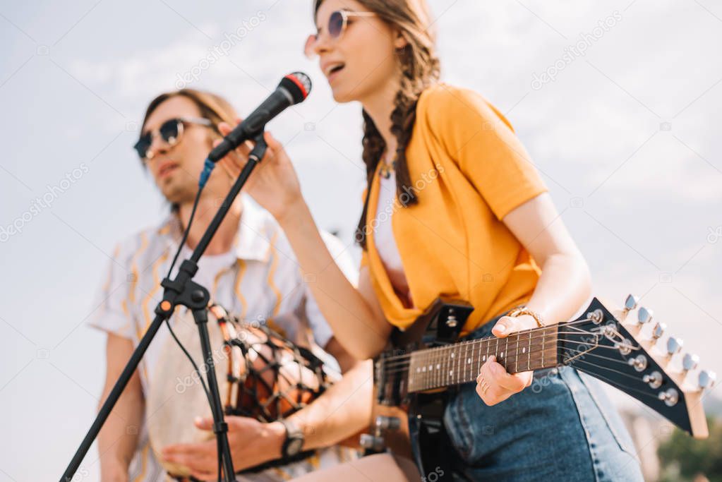 Couple of young friends playing music and singing in urban environment