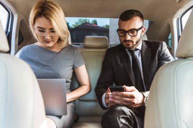 yakışıklı işadamı ve Yardımcısı araba laptop ve smartphone ile çalışma